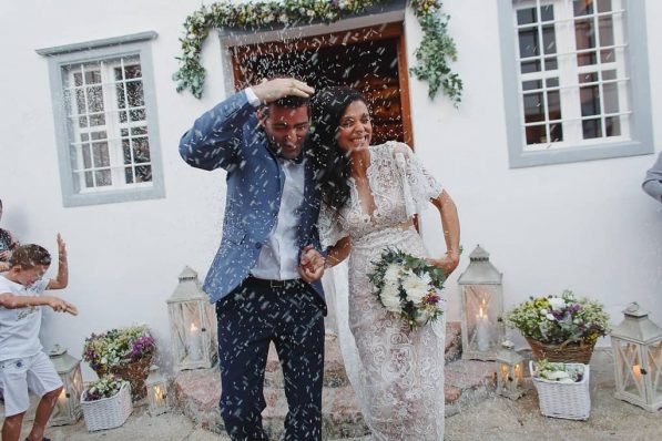 Bride and groom leaving the church while guests throw rice at them.