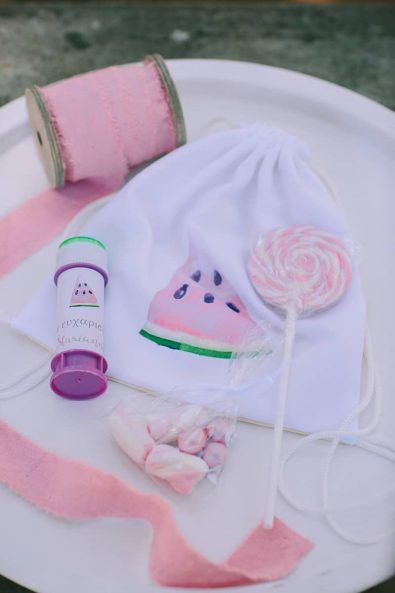 Children baptism ceremony party favors idea with lollipops, marshmallows, bubbles and pouch bag with watermelon print.