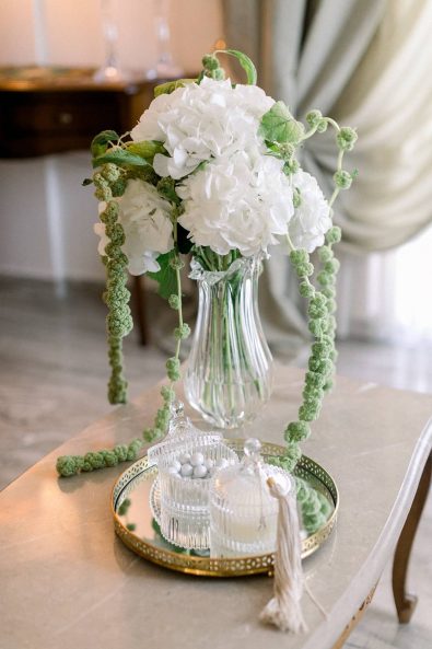 White hydrangeas in a crystal vase and crystal candy boxes with sugar-coated almonds and blush tassel on the lid.