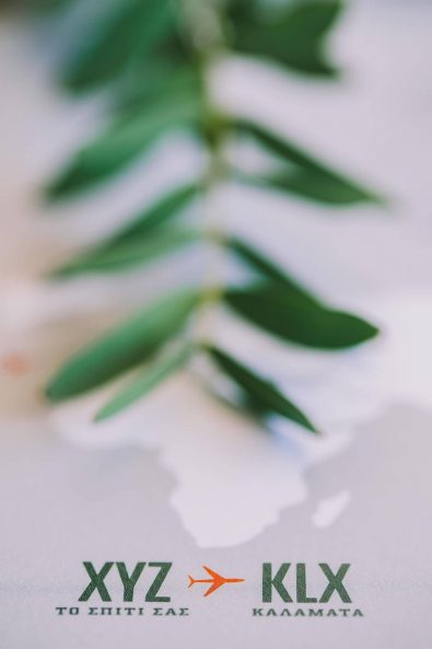 Close up shot of destination wedding invitation and olive leaves for a destination wedding in kalamata.