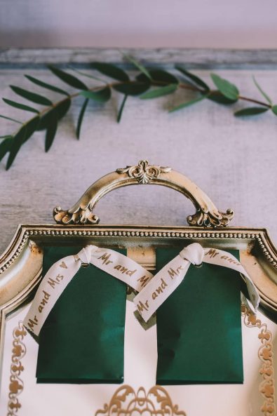 Forest green envelopes filled with rice and closed with a Mr and Mrs ribbon, on a mirror surface vintage tray for a destination wedding in kalamata.