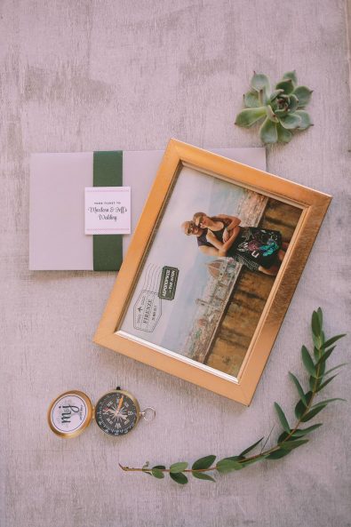Detail shot of bride and groom framed picture, compass, and invitation.