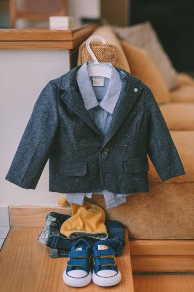 Boy's christening clothes with a blue suit and blue converse all star shoes for a baby baptism.