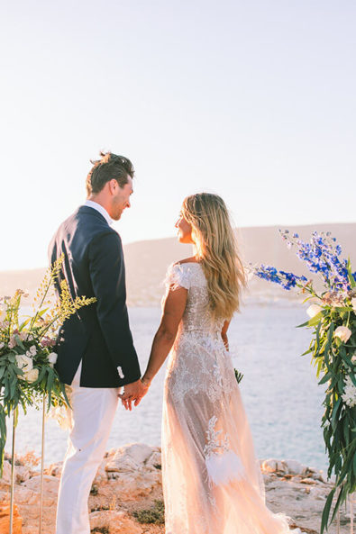 Bride and groom holding hands between flower stands