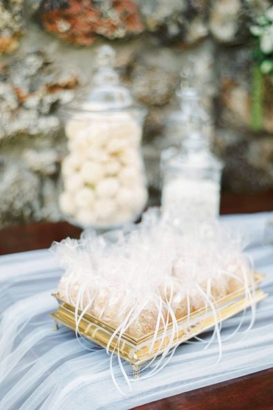 Simple tulle wedding favors on a gold tray.