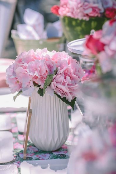 Pink summer hydrangea flowers on a white vase for a baptism ceremony.