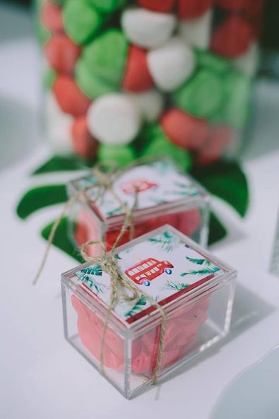 Boy's Christening baby baptism favors with plexiglass boxes decorated with a red bus and natural string, filled with koufeta wrapped in red tissue paper.