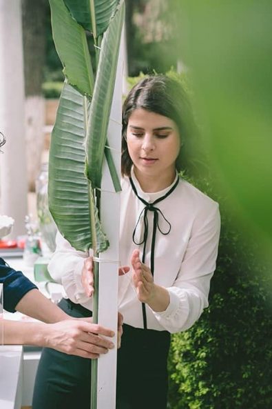 Beautiful female artists working hard to create a beautiful banana leaves backdrop for the baptism's candy bar.