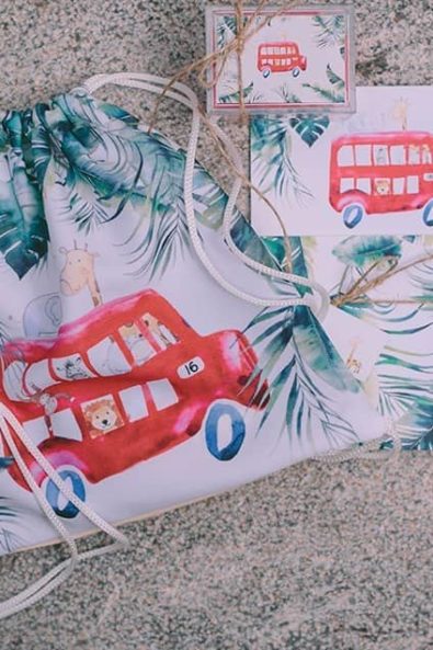 Christening box favors, printed bag favors and printed notebook all with a red bus, jungle animals and green leaves print.