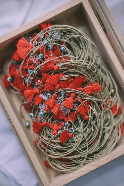 boy baptism witness pins, first communion favor bracelets with little red tassels, little plexiglass crosses, and evil eye beads.