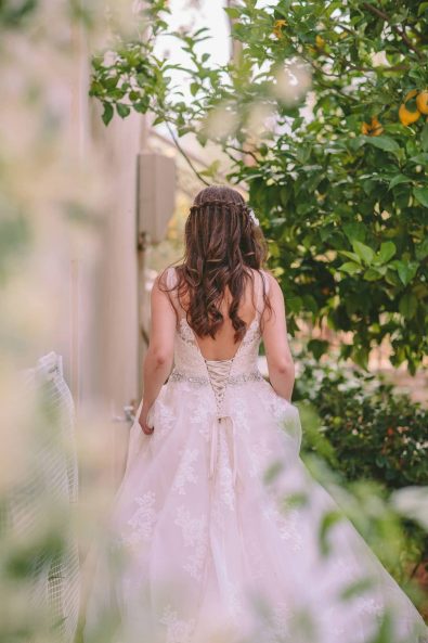 Bride's romantic bridal dress backline and waterfall braid hairstyle with loose waves for a destination wedding in kalamata.