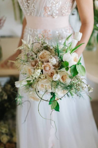 Summer bridal bouquet with white tulips, white and blush peonies, wildflowers, and vines.