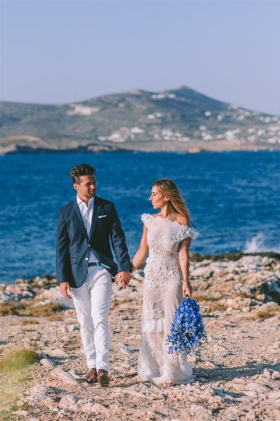 bride and groom holding hands in front of sea