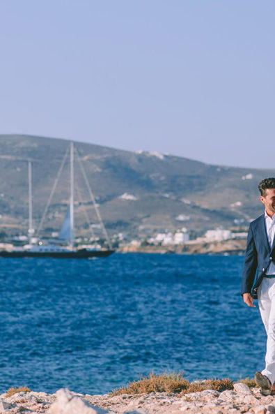 Bride and groom walking next to sea blue sea at their elopement in Paros