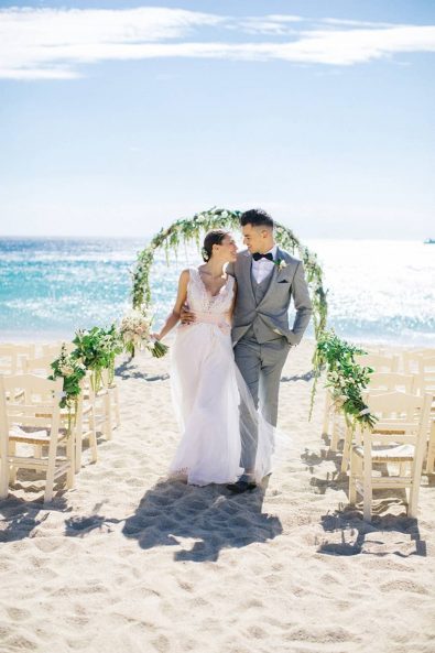 Bride and groom walking on the sand after their beach Mykonian wedding.