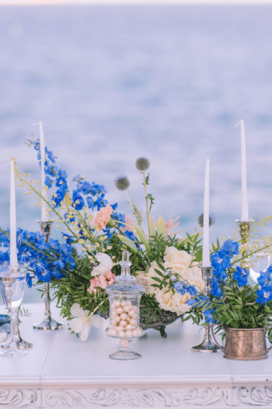 Wedding table with a big centerpiece, candles and art de la table elements, in white and blue colors