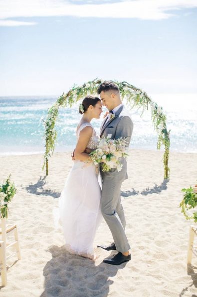 Bride and groom in a romantic embrace on the beach after their wedding ceremony.