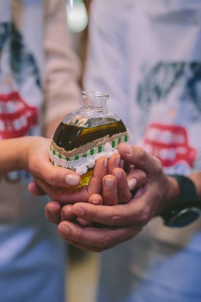 The Godfather and the godmother holding the glass bottle with the oil before an orthodox christening boy baptism ceremony.