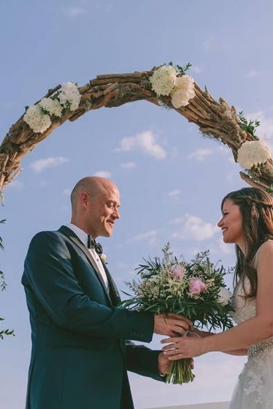 Bride and groom first look under the white hydrangea decorated wedding arch at a destination wedding in kalamata.