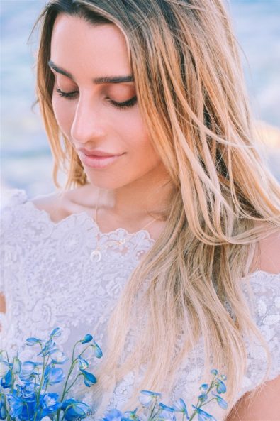 blonde woman looking down at her flowers at an elopement in Paros