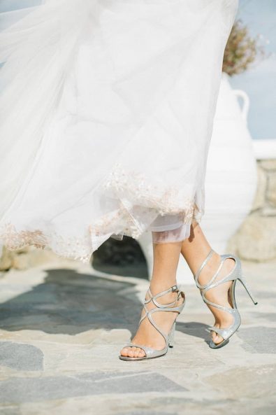 Bride's legs while she wears a pair of silver sparkling wedding high heel sandals.