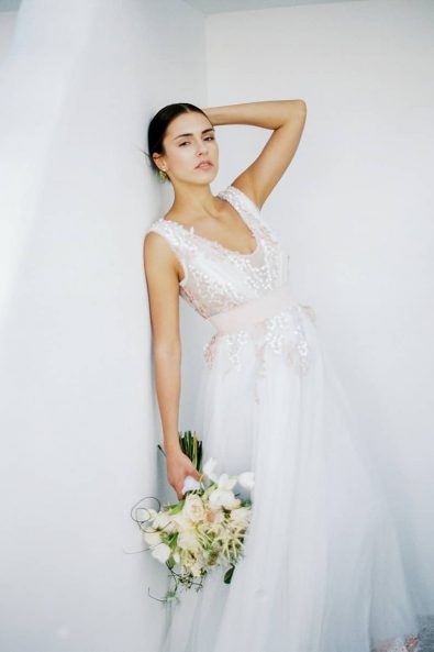 Bridal portrait of the bride looking seductively at the photographer wearing her blush and white wedding dress and holding her bridal bouquet.