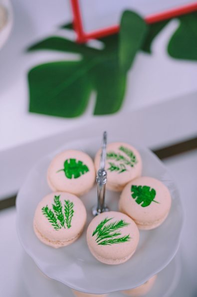 Five cream colored macarons with hand painted leaf patterns for a baby baptism.