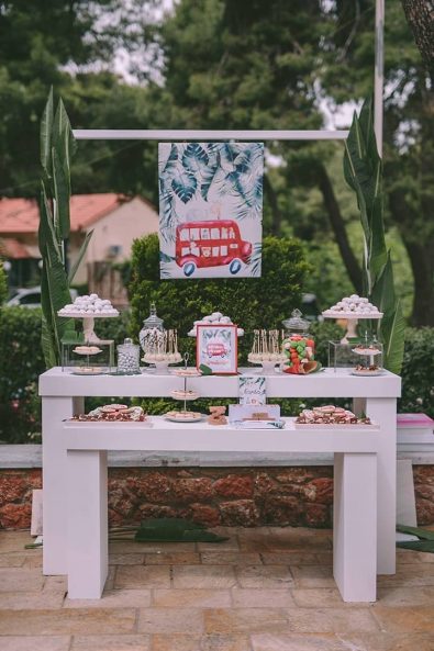 baby baptism candy bar with white tables and green leaves decoration with christening sweets, koufeta, biscuits, macarons and cake pops.