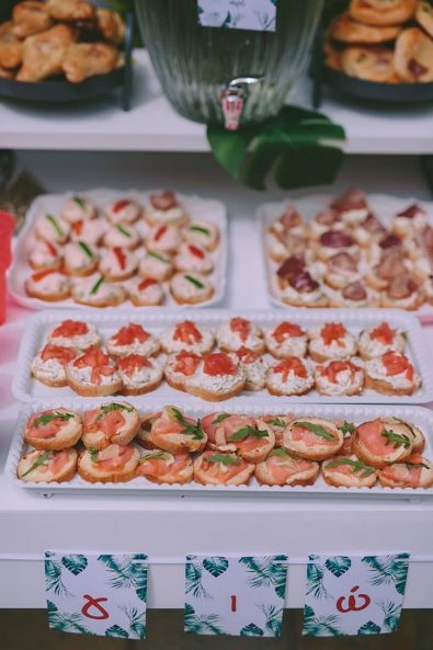Salmon and cream cheese canapes, tomato and feta cheese canapes in white trays for a buffet in a baptism after party.