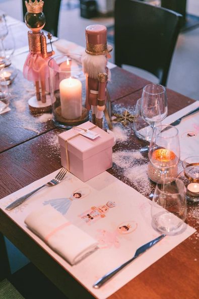 Festive nutcracker inspired christening reception table setting with custom made placemats, glitter, and pink box baptism favors.