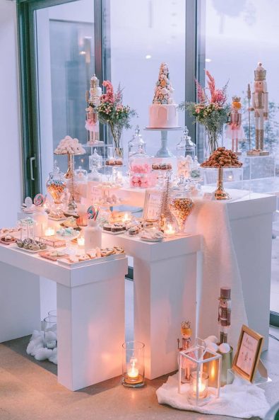 Light pink, blue and white candy bar dessert table with nutcrackers, candles and pampas grass flower arrangements.