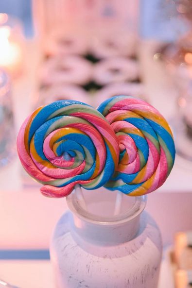 Swirly multicolor lollipops in a white vase.