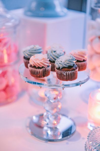Close up shot of mini chocolate cupcakes with pastel colored buttercream white sprinkles and sugar glitter.