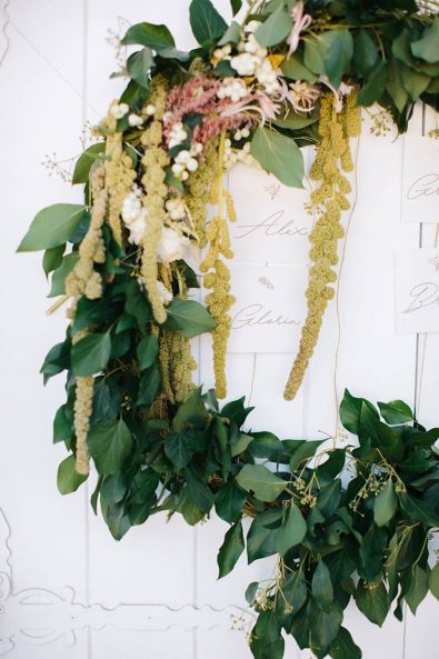 Summer boho wedding flower wreath decoration with greenery, white amaranthus and hypericum berries.