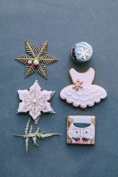 Close up shot of custom made nutcracker ballet inspired snowflake, ballet dress and nutcracker biscuits, chocolate cupcake with light blue frosting and snowflake Christmas ornament.