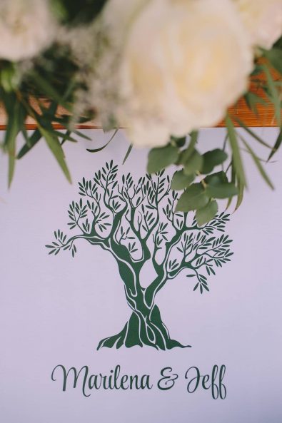 Wedding welcome sign with couple's names and a deep green olive tree outline for a destination wedding in kalamata.