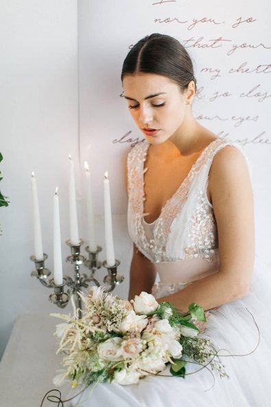 Beautiful bride holding her flower bouquet photographed next to a candelabra candle holder.