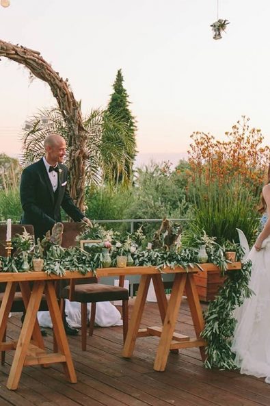 Bride and groom taking their places in the bridal table at the beginning of their wedding dinner party at a destination wedding in kalamata.