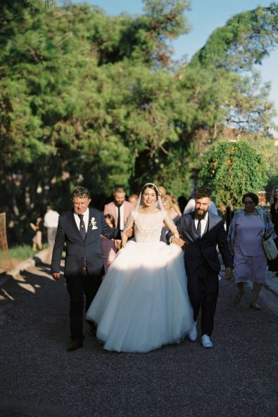 The father and the brother of the bride walking her to the church in the sunset.
