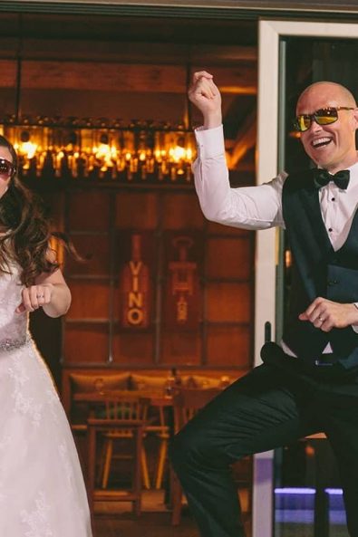 Bride and groom dancing Gangnam style on their wedding party wearing sunglasses.
