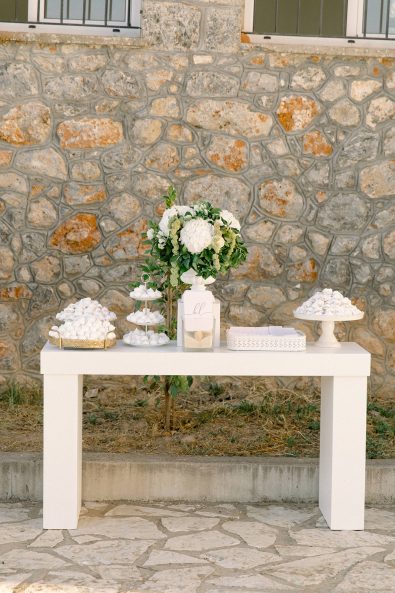 White table filled with candies in front of stone wall