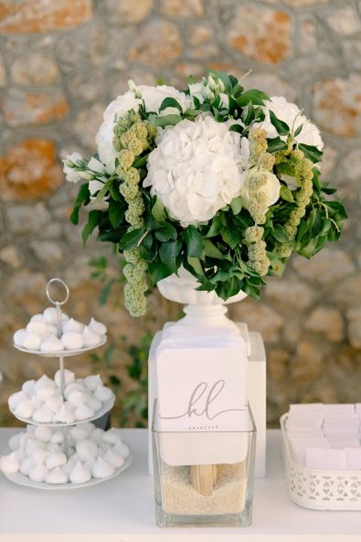 Classy flower arrangement with white hydrangeas and green leaves.