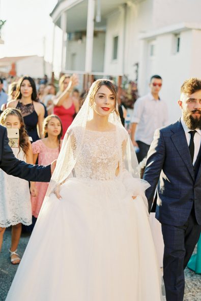Bride being walked to groom by two men in suits