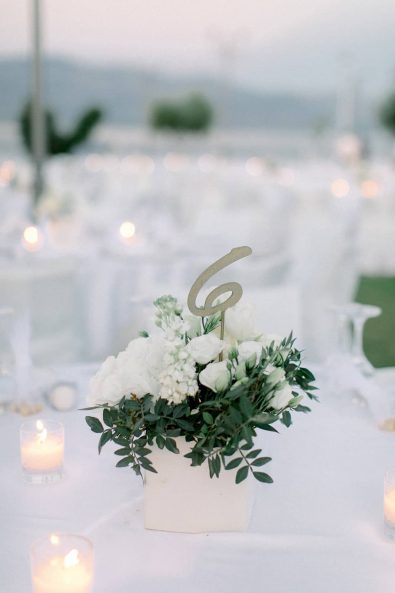 Table numbers in white boxes with flower and greenery.