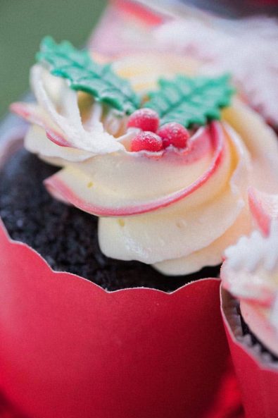 Festive red and white buttercream with mistletoe fondant decorations in red paper cupcake cases.