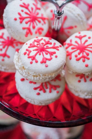 White french macarons with red snowflakes on top for a private Christmas dinner dessert table.