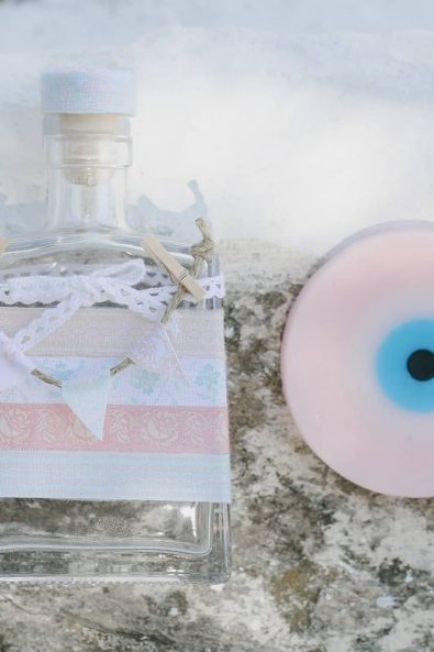 christening ideas - Square oil bottle with fabric decorations and pink evil eye soap.