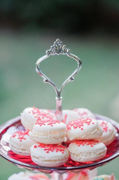 White chocolate ganache filled macarons decorated with red snowflakes out of royal icing.