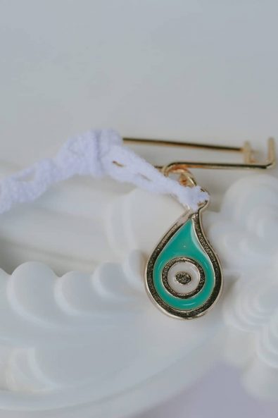 Teal evil eye martirika pin with white lace ribbon.