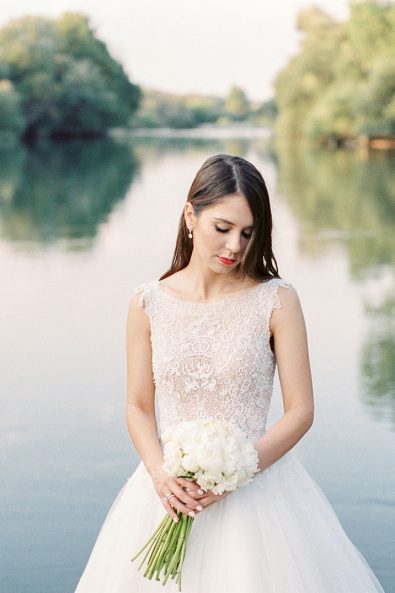Bride holding bouquet in front of lake at her wedding in Messolonghi